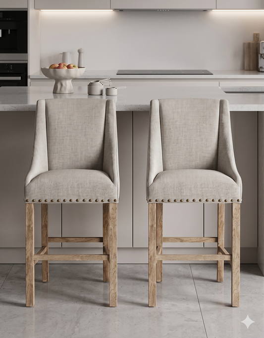 Banqueta alta de diseño contemporáneo con estructura de madera maciza en acabado natural. Presenta un asiento y respaldo integrado, tapizado en pana color claro con textura sutil. Incluye apoyapiés perimetral de madera para mayor estabilidad y confort