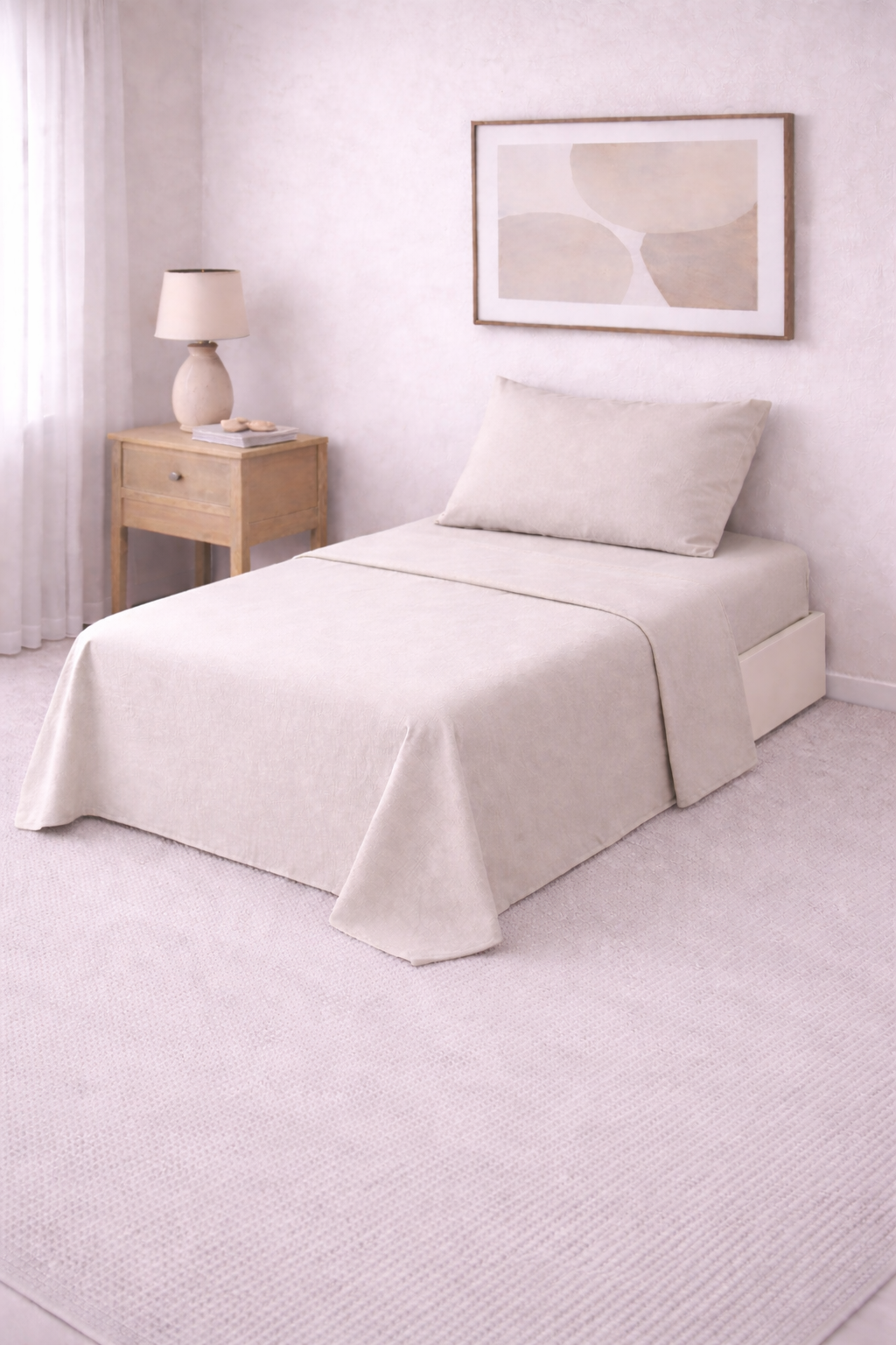 Cama de una plaza con sábanas lisas en tono suave, perfectamente tendida en un dormitorio luminoso de estilo minimalista con mesa de luz de madera y decoración neutra.