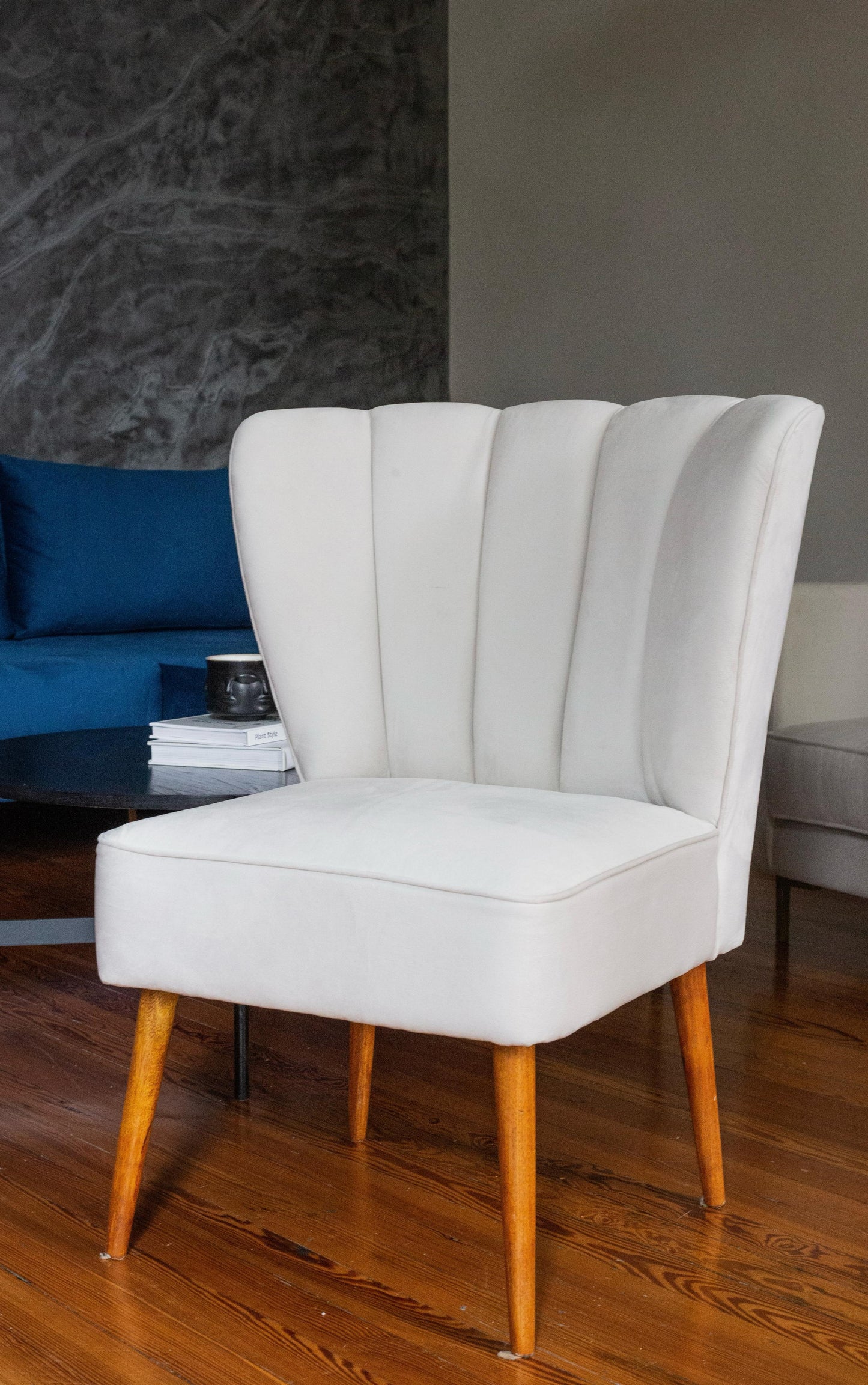 Butaca tapizada blanco con respaldo en forma de pétalos y patas de madera. Ideal como sillón decorativo o infantil para espacios modernos.
