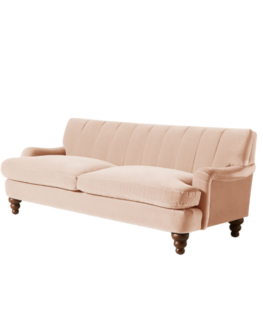 Vista completa del sofá modelo Malaika tapizado con respaldo vainillado profundo, brazos curvos y elegantes patas de madera oscura torneada, ubicado sobre fondo blanco, ideal para salas de estar, livings modernos o espacios clásicos que buscan un mueble llamativo y sofisticado.