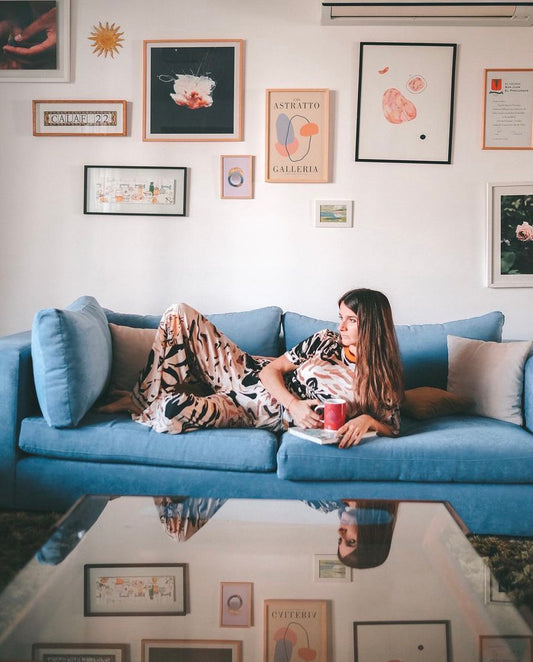 Un sillón esquinero en pana azul, acompañado de almohadones en tonos beige y rosados, que aportan contraste y calidez en un living de estilo moderno y acogedor