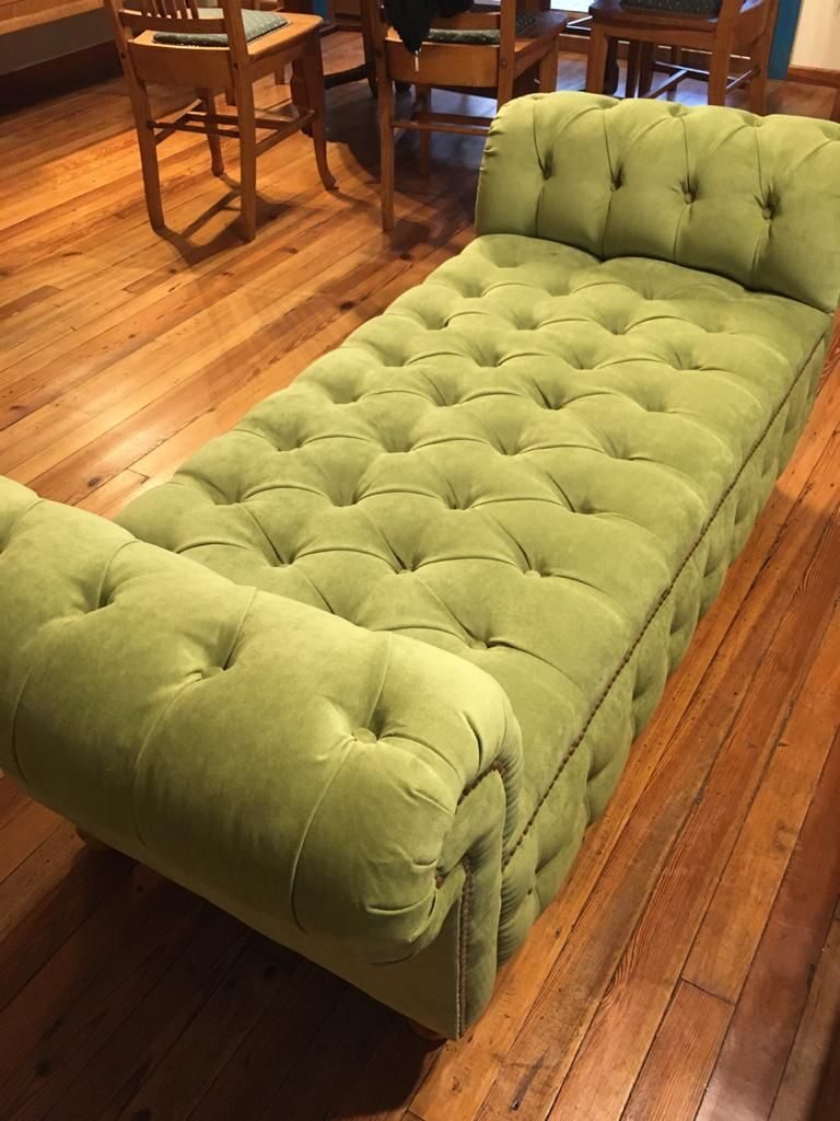 Detalle diván Chesterfield verde oliva con capitoné completo sobre parquet de madera natural en hogar Argentina – Tienda de Banquitos