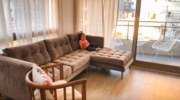 Esquinero a medida en pana antimanchas color tabaco, con capitoné en cuadrícula y un nene sentado en el chaise, junto al balcón del living de Simon en Jujuy