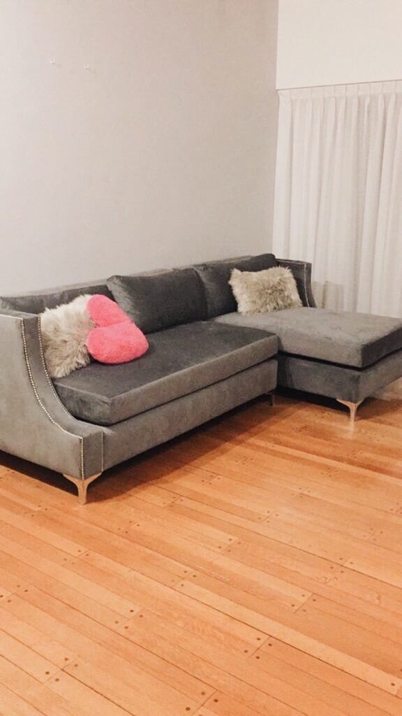 Esquinero en velvet gris oscuro con chaise, tachas en los apoyabrazos y patas metálicas, en el living de Susana