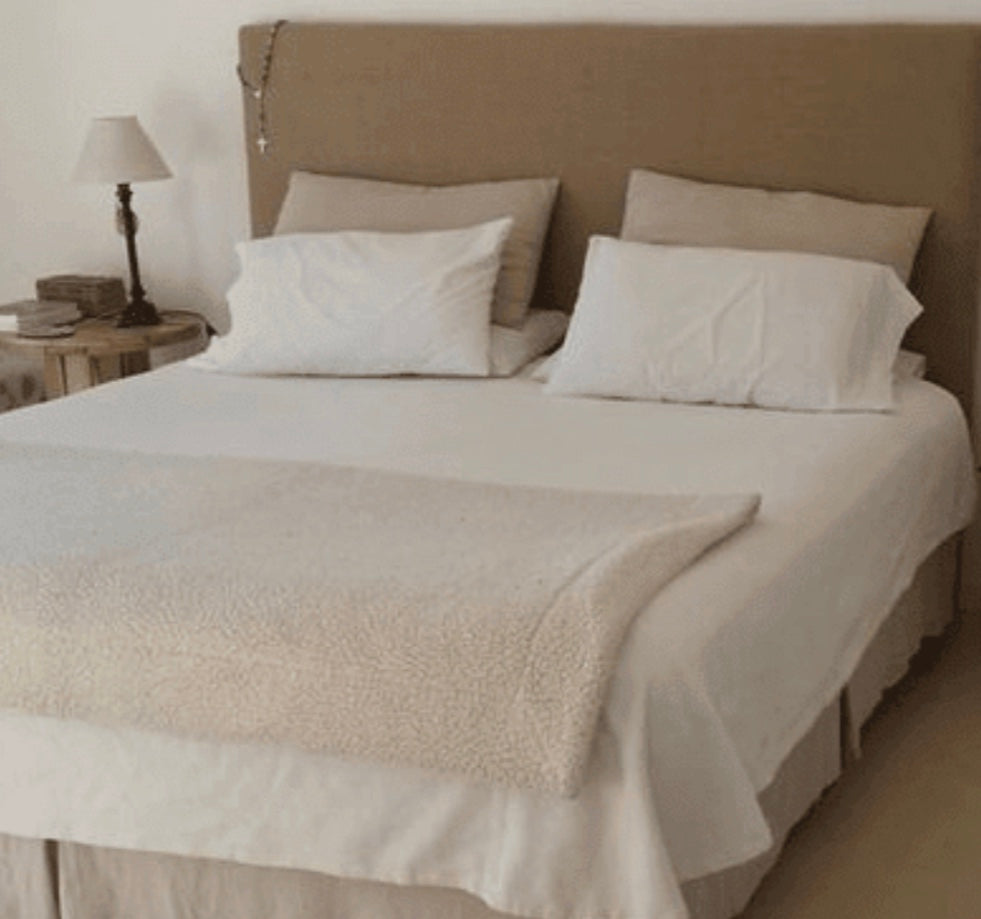 Respaldo Simply en taupe, liso y sin costuras, con ropa de cama blanca y una mesa de luz de madera rústica, en el dormitorio de Florencia en Rosario