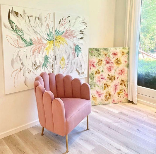 Sillón Angie rosa de respaldo curvo y patas doradas junto a un ventanal y cuadros de flores, en el espacio de Maluhia by Matilde