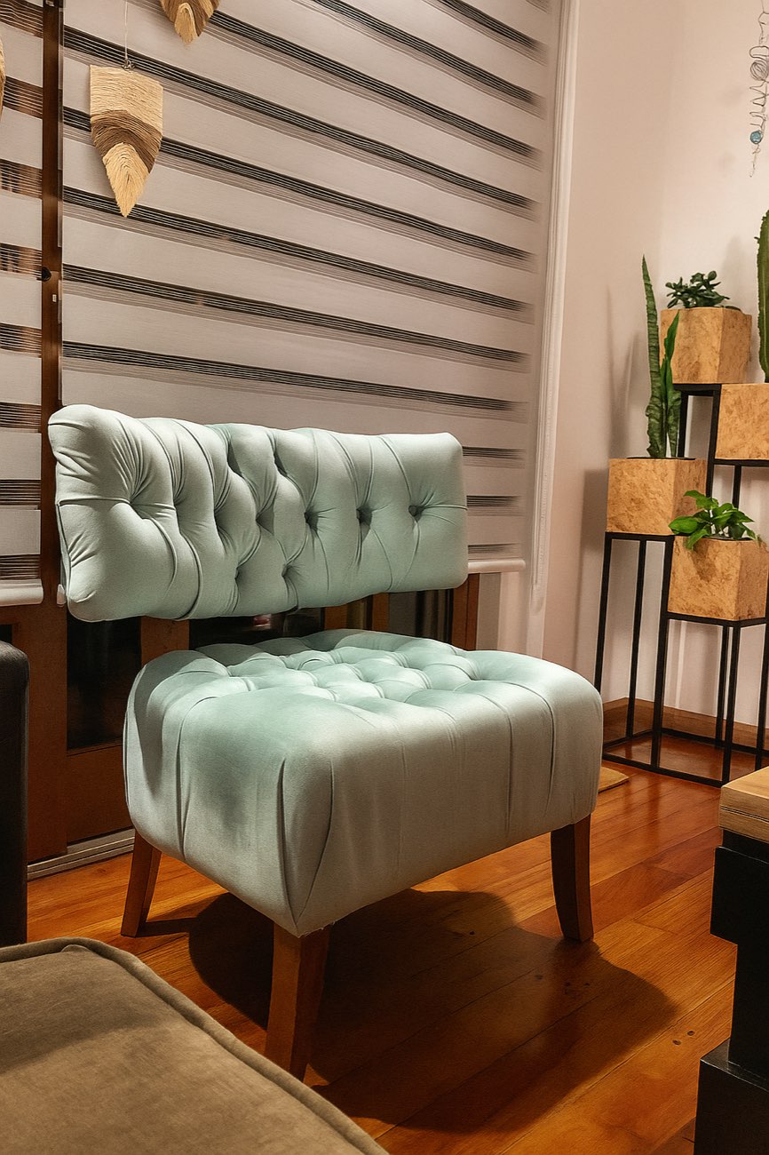 Sillón Matero Rosella en pana color acqua, con capitoné en respaldo y asiento y patas de madera, en el rincón de lectura de Julieta