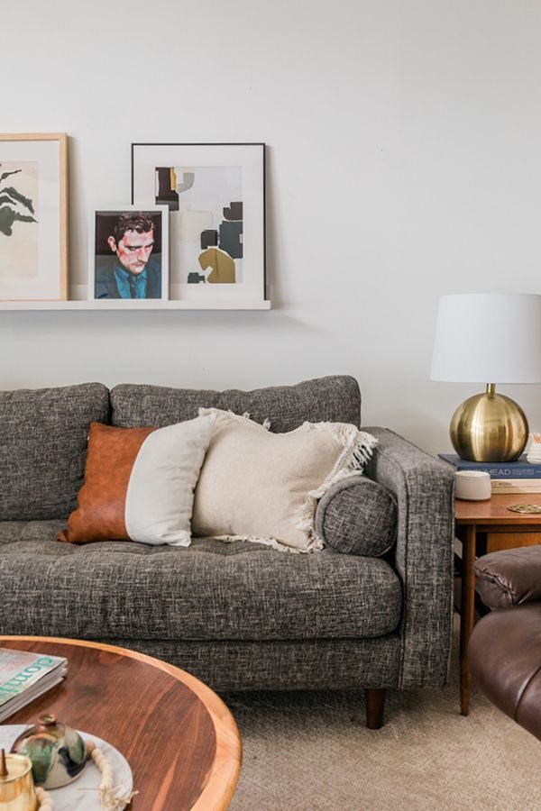 Sofá Chesterfield Capitoné gris en living con cuadros y arte en estante | Tienda de Banquitos Argentina