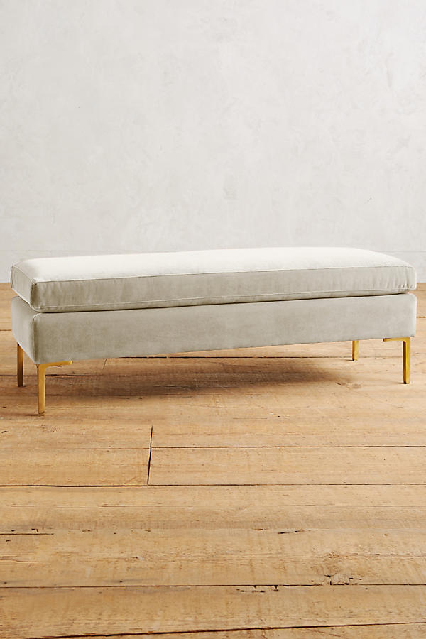 Banqueta de diseño moderno tapizada en crema con patas metálicas doradas. Ideal para pie de cama, recibidores o livings.