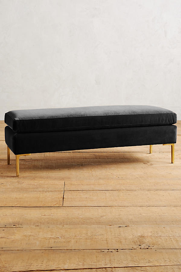 Banqueta de diseño moderno tapizada en negro con patas metálicas doradas. Ideal para pie de cama, recibidores o livings.