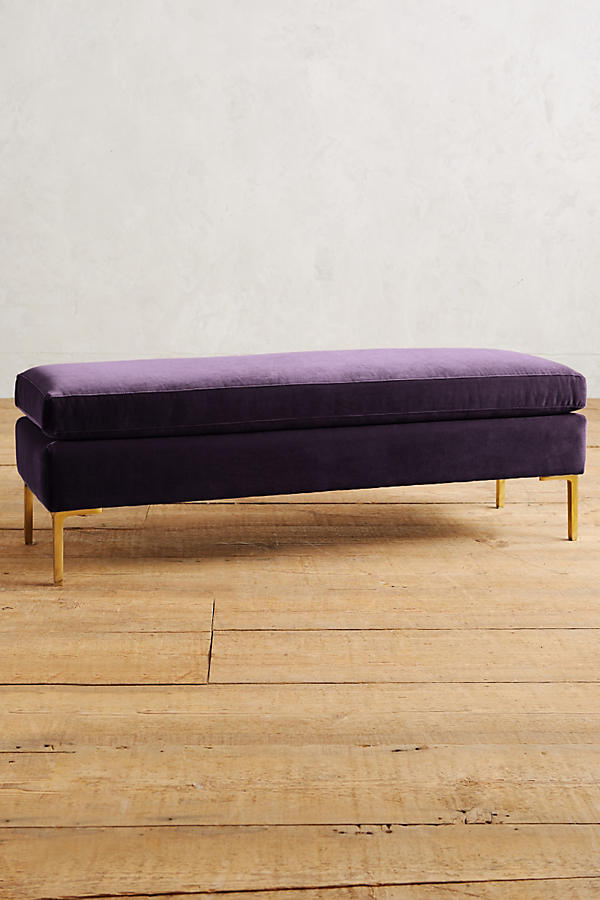 Banqueta de diseño moderno tapizada en violeta con patas metálicas doradas. Ideal para pie de cama, recibidores o livings.