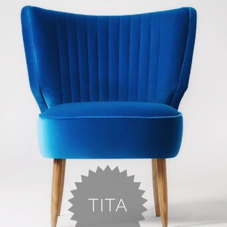 Sillón tapizado en celeste con respaldo curvo acanalado y patas de madera clara. Perfecto para espacios infantiles o rincones de lectura.