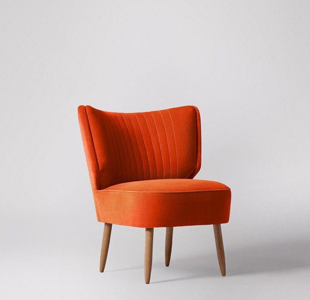 Sillón matero con franjas verticales en el respaldo color rojo anaranjado, con patas roble claro