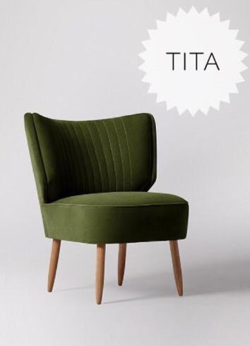 Sillón tapizado en verde con respaldo curvo acanalado y patas de madera clara. Perfecto para espacios infantiles o rincones de lectura.