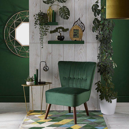 Butaca pequeña tapizada en verde con respaldo vertical y patas cónicas. Diseño minimalista ideal para niños o espacios reducidos.