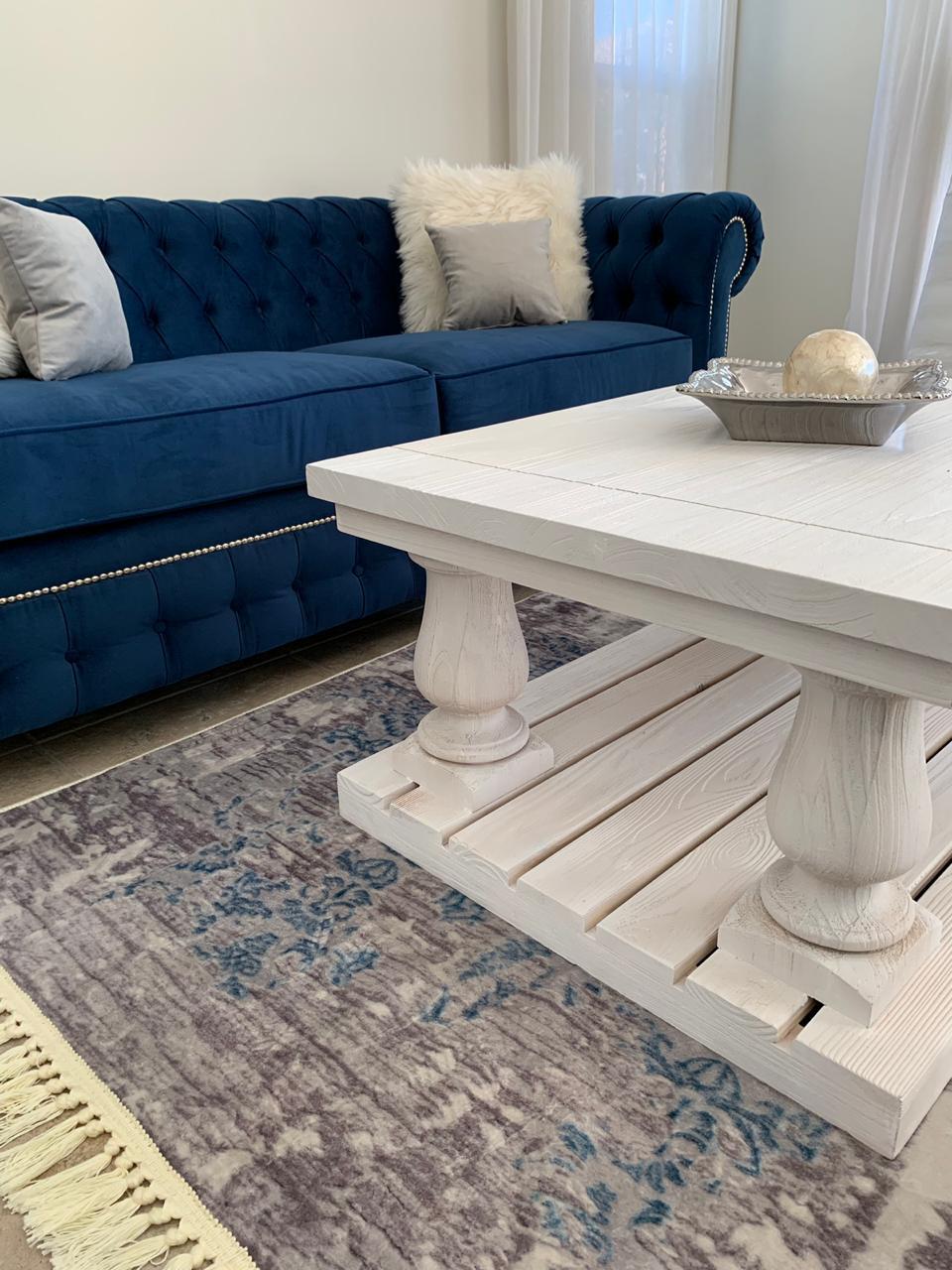 Juego de sillones con tapizado capitoné en tonos azul marino y gris, de diseño elegante y clásico, ubicados en un living luminoso con decoración sofisticada