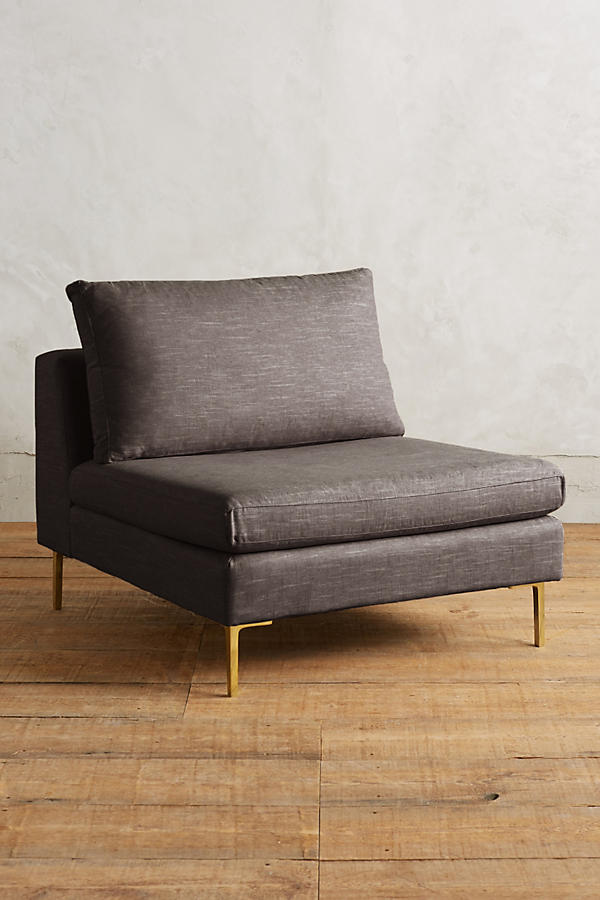 Módulo de sillón sin apoyabrazos en color gris, con respaldo alto y almohadón mullido, patas metálicas delgadas en tono dorado, sobre fondo blanco.
