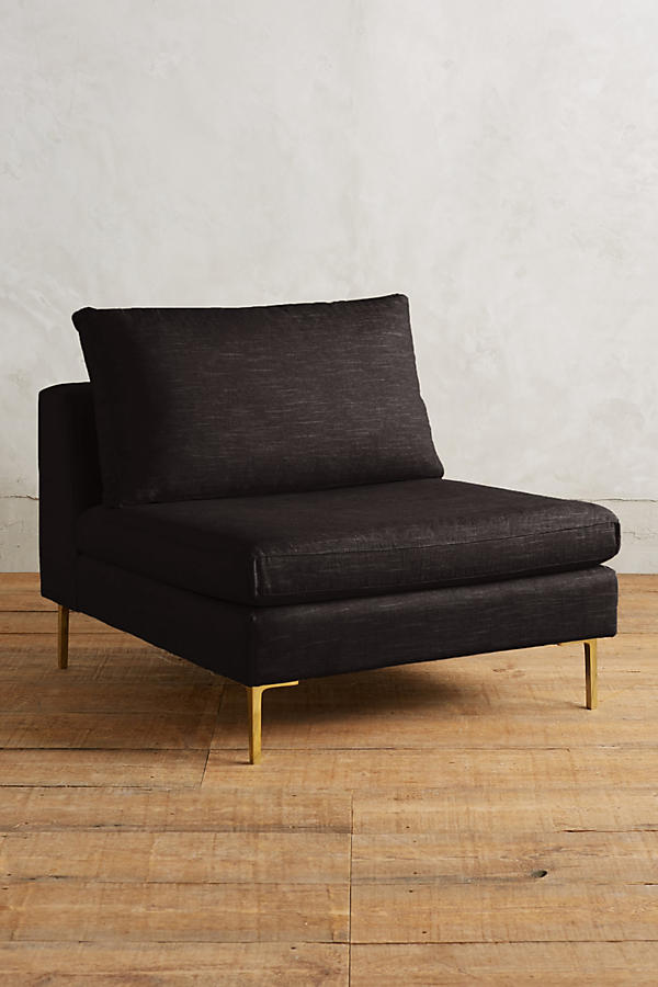 Módulo de sillón sin apoyabrazos en color negro, con respaldo alto y almohadón mullido, patas metálicas delgadas en tono dorado, sobre fondo blanco.