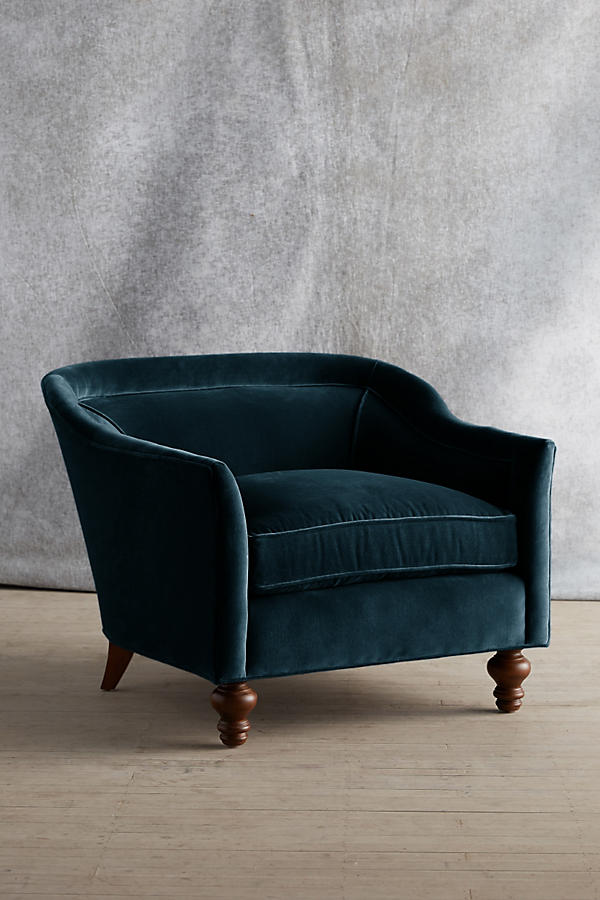 Sillón individual tapizado en color petroleo, con diseño de respaldo envolvente, asiento amplio y patas torneadas de madera oscura.