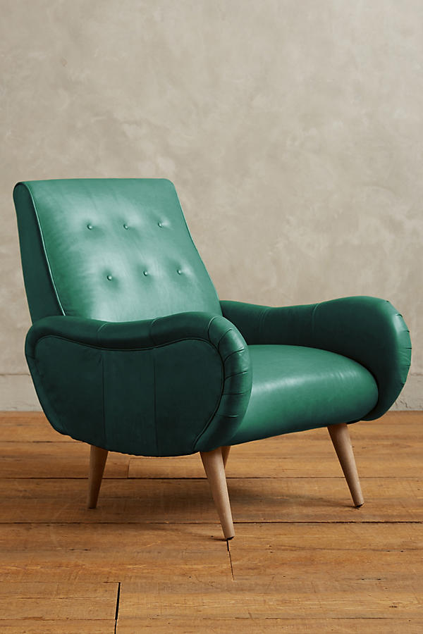Sillón de un cuerpo estilo retro tapizado en verde, con respaldo bajo capitoné, apoyabrazos curvos y patas de madera cónicas.