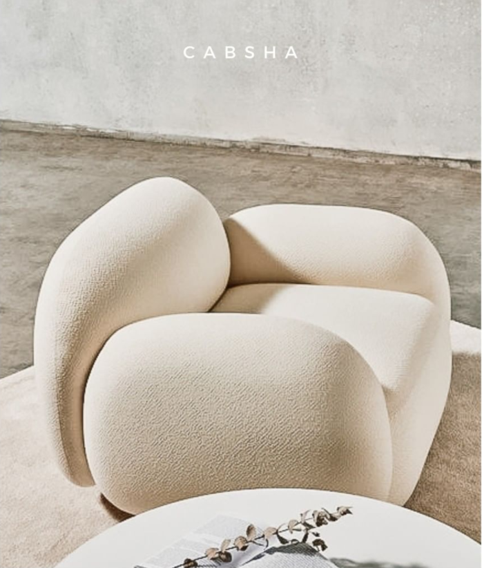 Sillón individual de diseño moderno y orgánico en color crema, con formas curvas y acolchadas en respaldo, asiento y apoyabrazos integrados