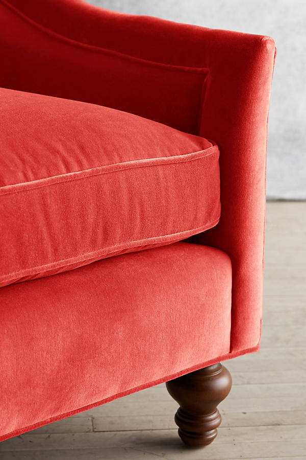 Sillón individual tapizado en color rojo, con diseño de respaldo envolvente, asiento amplio y patas torneadas de madera oscura.