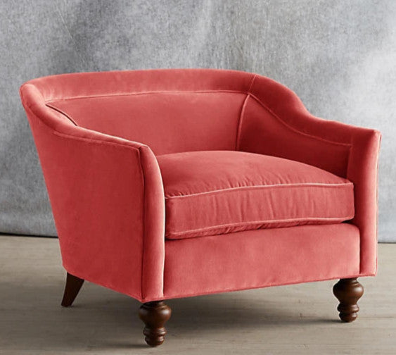Sillón individual tapizado en color rosa, con diseño de respaldo envolvente, asiento amplio y patas torneadas de madera oscura.