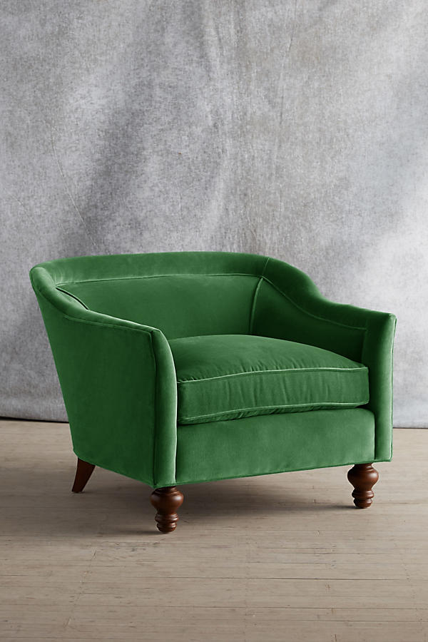 Sillón individual tapizado en color verde, con diseño de respaldo envolvente, asiento amplio y patas torneadas de madera oscura.