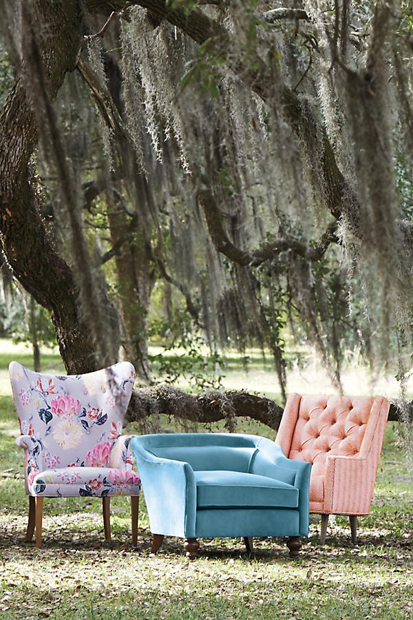 Sillón individual, con diseño de respaldo envolvente, asiento amplio y patas torneadas de madera oscura.