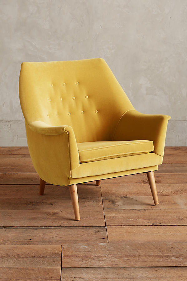 Sillón individual tapizado en amarillo, de diseño retro con respaldo inclinado, asiento acolchado y patas de madera inclinadas estilo escandinavo.