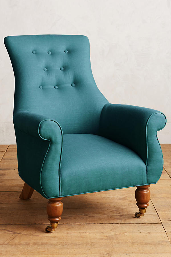 Sillón individual estilo clásico tapizado en aqua, con respaldo alto capitoné, apoyabrazos curvos y patas torneadas de madera.