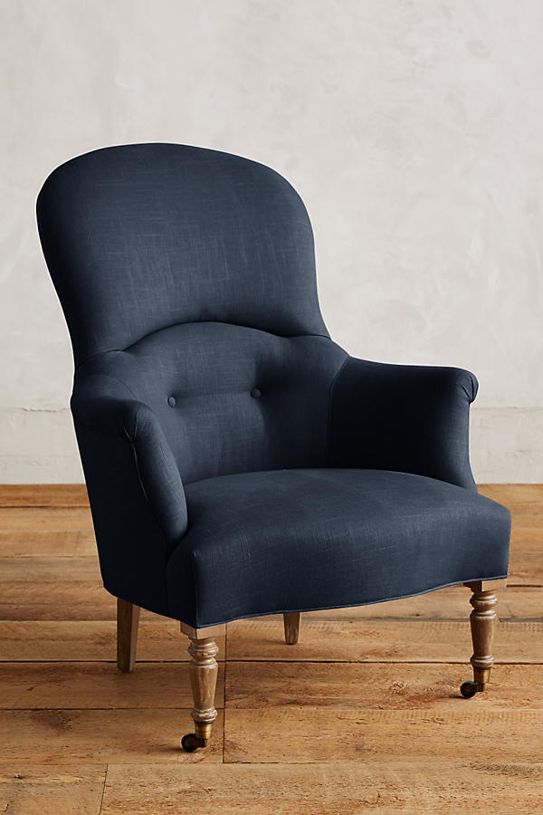 Sillón individual de diseño tradicional en tono azul, con respaldo curvo, apoyabrazos tallados y patas delanteras de madera con ruedas.