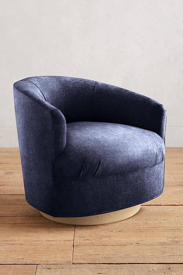 Sillón individual moderno con forma redondeada y base giratoria, tapizado en azul.