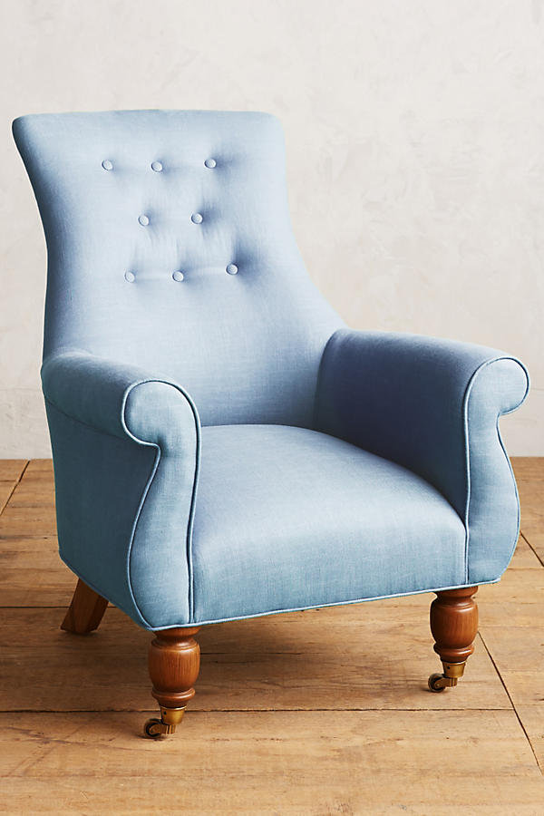 Sillón individual estilo clásico tapizado en celeste, con respaldo alto capitoné, apoyabrazos curvos y patas torneadas de madera.