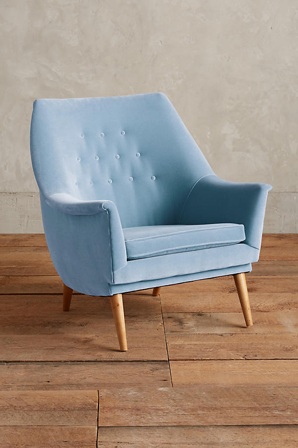 Sillón individual tapizado en celeste, de diseño retro con respaldo inclinado, asiento acolchado y patas de madera inclinadas estilo escandinavo.