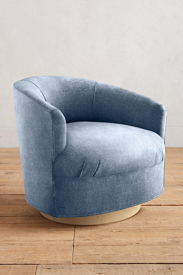 Sillón individual moderno con forma redondeada y base giratoria, tapizado en celeste.