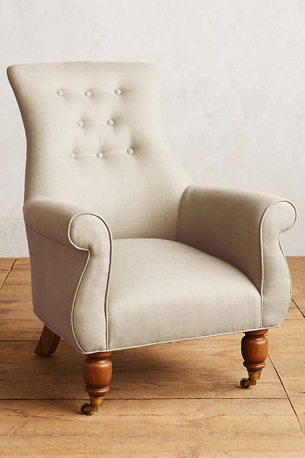 Sillón individual estilo clásico tapizado en crema, con respaldo alto capitoné, apoyabrazos curvos y patas torneadas de madera.