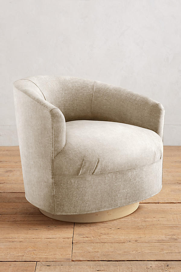 Sillón individual moderno con forma redondeada y base giratoria, tapizado en crema.