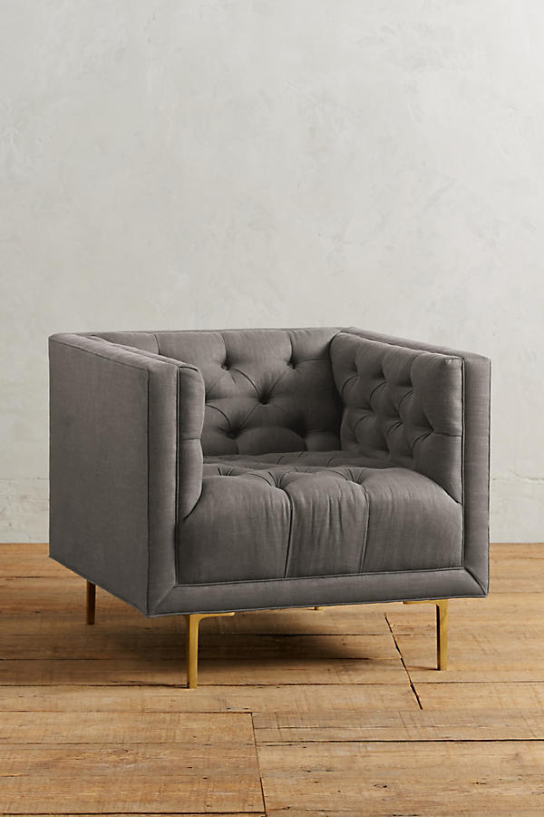 Sillón individual tapizado en rosa viejo, de forma cúbica con respaldo y brazos rectos, capitoné de botones en todo el interior y patas delgadas de madera.