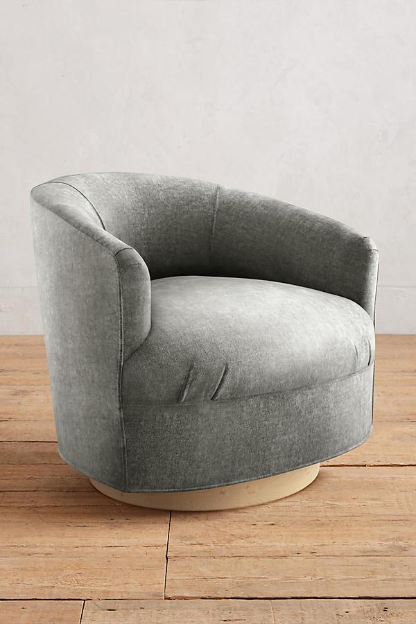 Sillón individual moderno con forma redondeada y base giratoria, tapizado en gris.