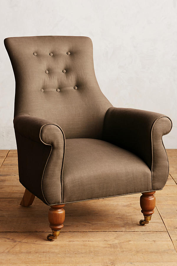Sillón individual estilo clásico tapizado en marron, con respaldo alto capitoné, apoyabrazos curvos y patas torneadas de madera.