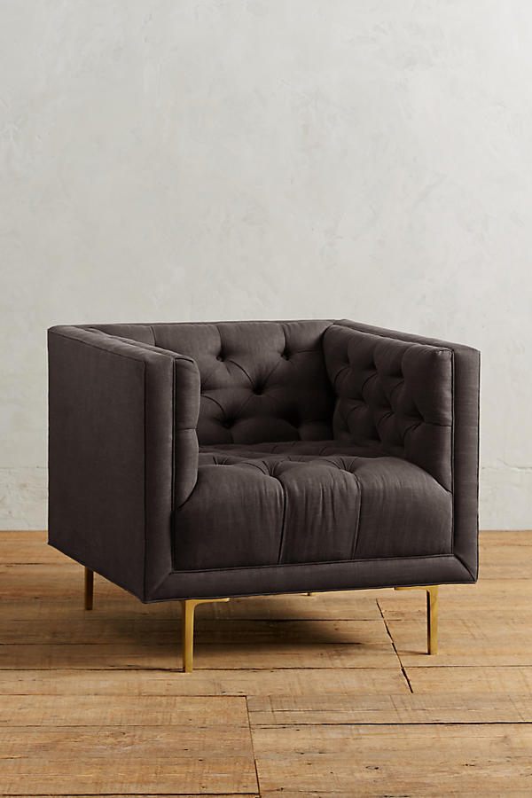Sillón individual tapizado en rosa viejo, de forma cúbica con respaldo y brazos rectos, capitoné de botones en todo el interior y patas delgadas de madera.