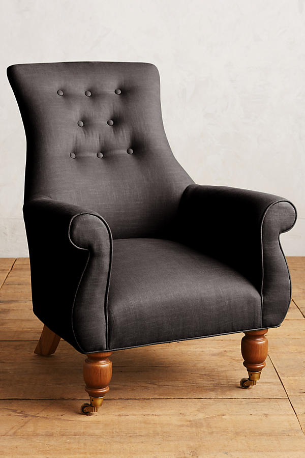 Sillón individual estilo clásico tapizado en negro, con respaldo alto capitoné, apoyabrazos curvos y patas torneadas de madera.