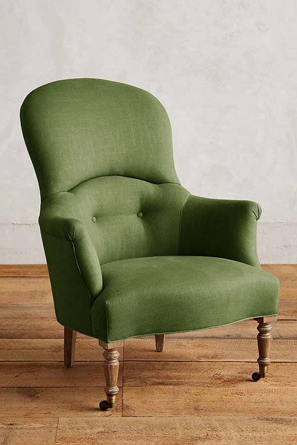 Sillón individual de diseño tradicional en tono oliva, con respaldo curvo, apoyabrazos tallados y patas delanteras de madera con ruedas.