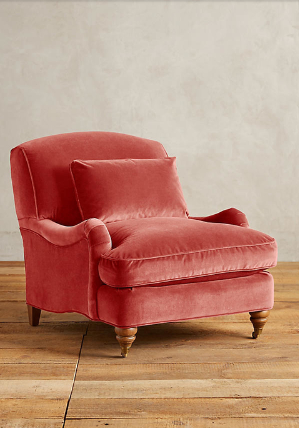 Sillón individual tapizado en rojo, con cojín lumbar suelto, apoyabrazos curvos, respaldo levemente inclinado y patas torneadas de madera en tono medio.