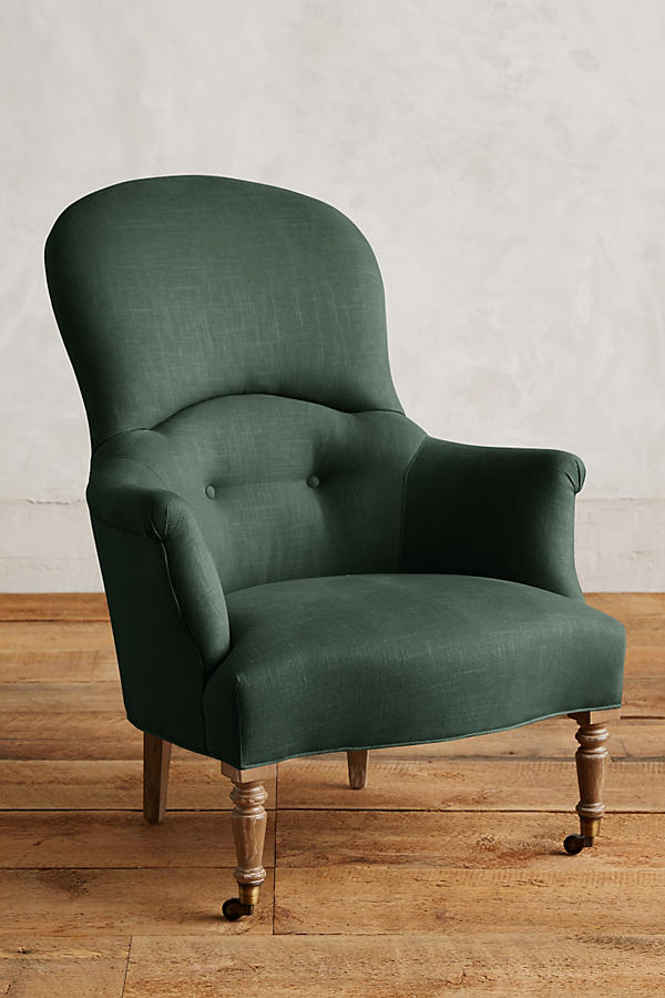 Sillón individual de diseño tradicional en tono verde, con respaldo curvo, apoyabrazos tallados y patas delanteras de madera con ruedas.