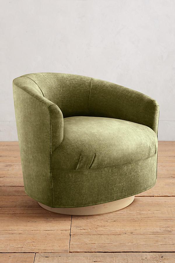 Sillón individual moderno con forma redondeada y base giratoria, tapizado en verde.