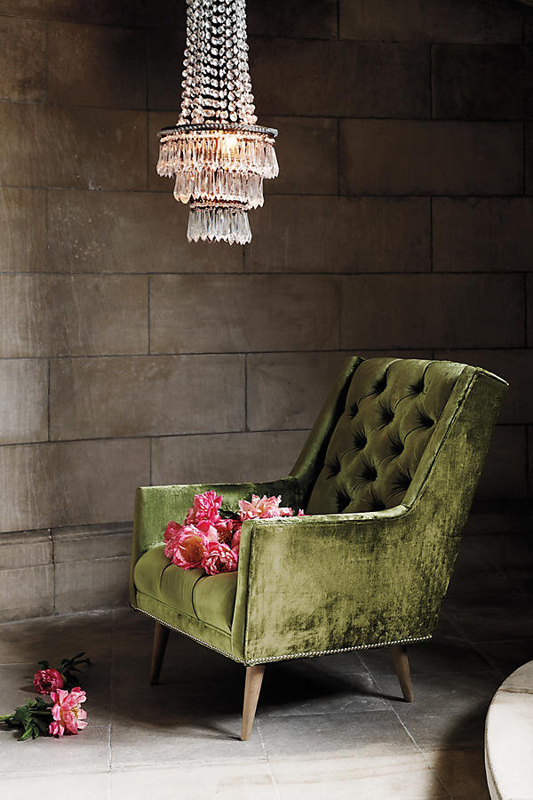 Sillón individual tapizado en verde, con respaldo capitoné de botones, brazos rectos y patas de madera inclinadas.