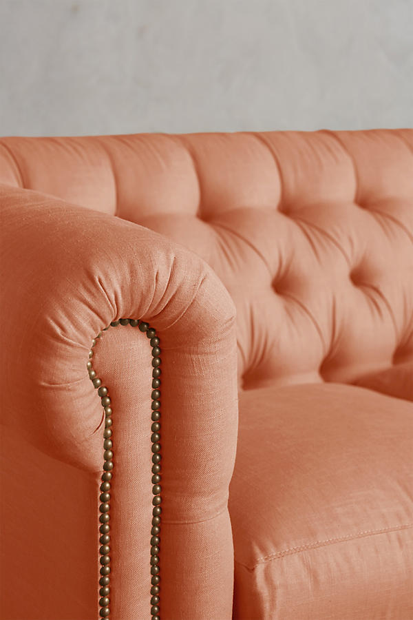 Detalle del brazo enrollado con tachas y el capitoné del Sillón esquinero Chesterfield en rosa salmón