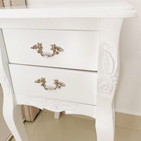 Mesa de Luz Bailarina Gillis laqueada en blanco, con dos cajones, tiradores plateados y tallas de hojas y flores